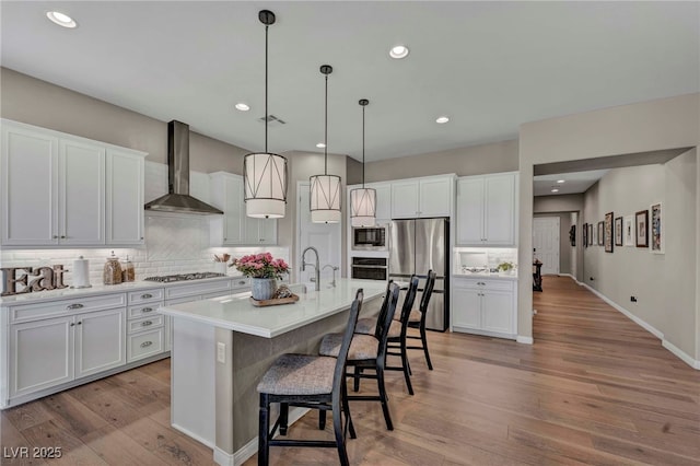 6325 Gambetta St, Las Vegas, NV 89115 - kitchen featuring a kitchen breakfast bar, wall chimney exhaust hood, stainless steel appliances, white cabinetry, and backsplash
