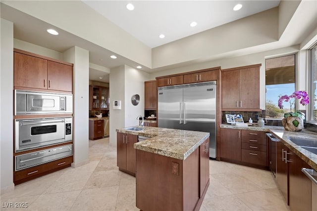 kitchen featuring built in appliances, a kitchen island with sink, recessed lighting, a sink, and a warming drawer