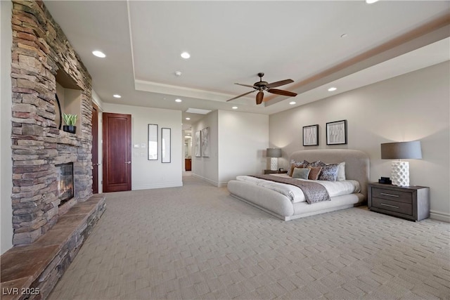 bedroom featuring a fireplace, baseboards, recessed lighting, a tray ceiling, and carpet