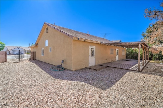 back of house with fence, a wooden deck, and stucco siding