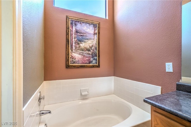 bathroom with vanity, a textured wall, and a garden tub