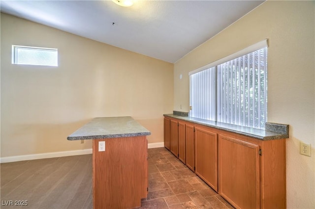 kitchen with dark countertops, baseboards, brown cabinetry, and a peninsula