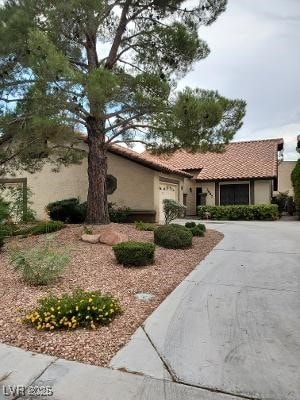 mediterranean / spanish-style home featuring stucco siding, a tiled roof, driveway, and a garage
