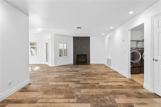 unfurnished living room featuring visible vents, wood finished floors, recessed lighting, a large fireplace, and separate washer and dryer