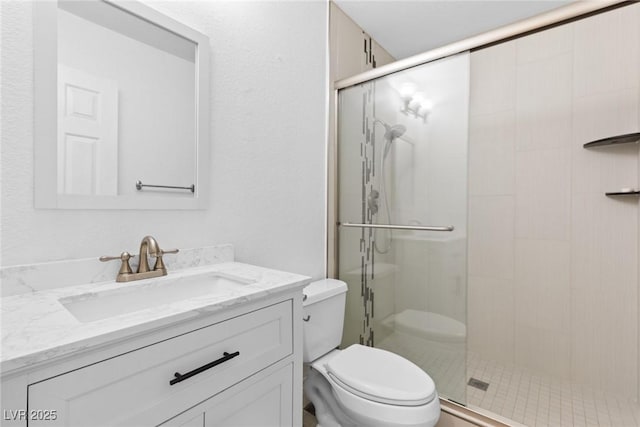 full bathroom featuring vanity, a stall shower, and toilet