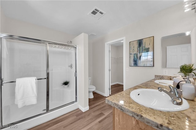full bathroom featuring visible vents, a stall shower, wood finished floors, a sink, and toilet