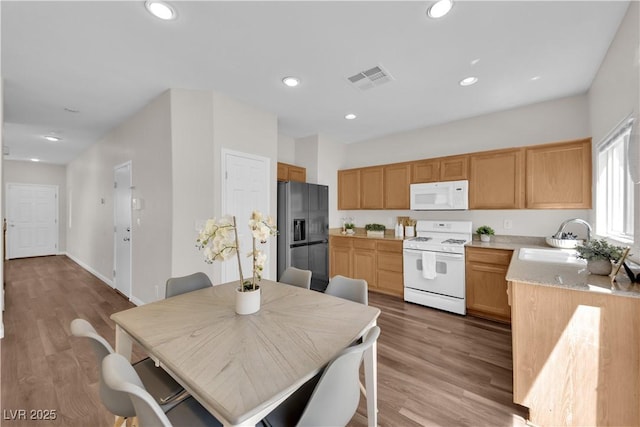 kitchen with a sink, white appliances, light countertops, recessed lighting, and visible vents