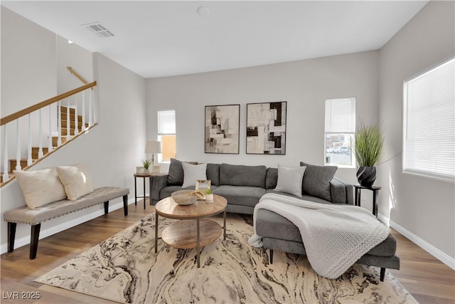living area featuring visible vents, baseboards, stairs, and wood finished floors