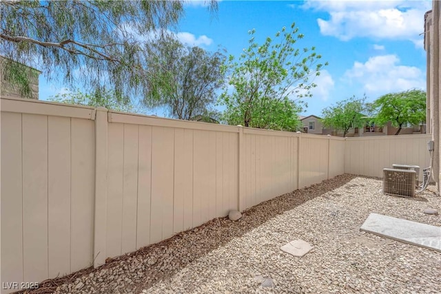 view of yard with central AC and fence