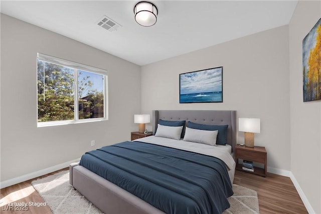 bedroom with visible vents, baseboards, and wood finished floors