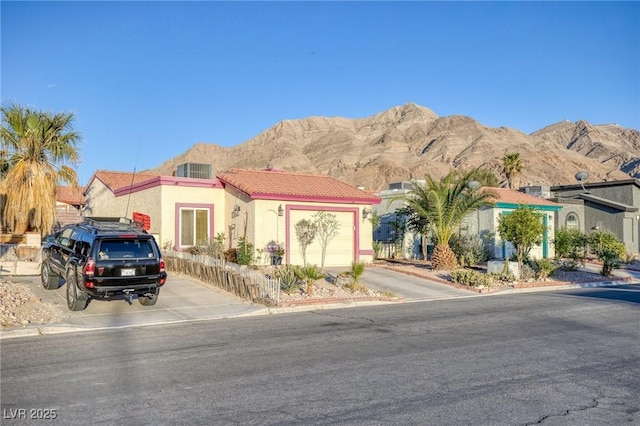 view of front facade featuring stucco siding, a garage, a mountain view, and a tiled roof