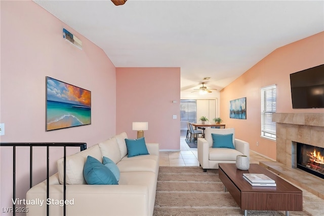 living room with a healthy amount of sunlight, a ceiling fan, vaulted ceiling, and a fireplace