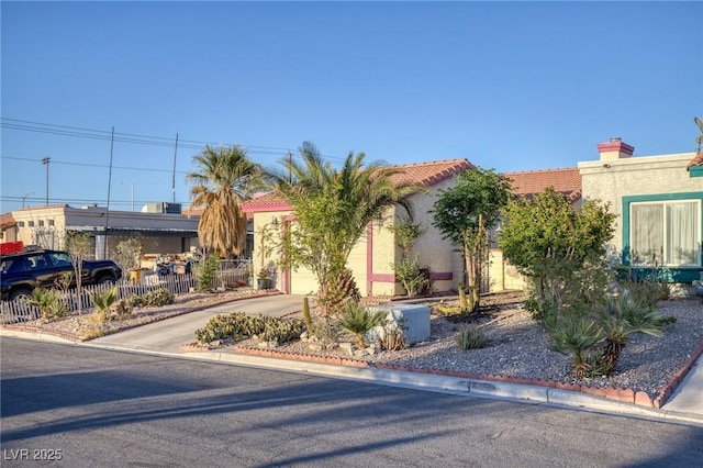 view of front of home featuring driveway, a tile roof, a garage, fence, and stucco siding