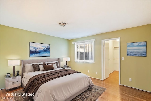 bedroom featuring baseboards, visible vents, and light wood finished floors