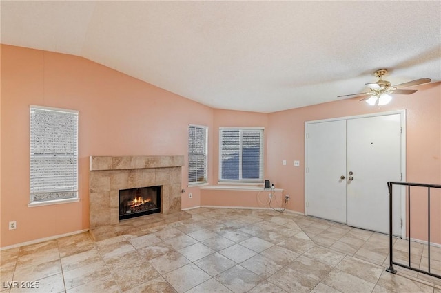 unfurnished living room featuring baseboards, ceiling fan, lofted ceiling, and a tile fireplace