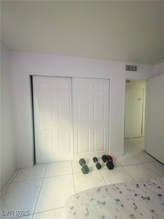 unfurnished bedroom featuring visible vents, marble finish floor, and a closet
