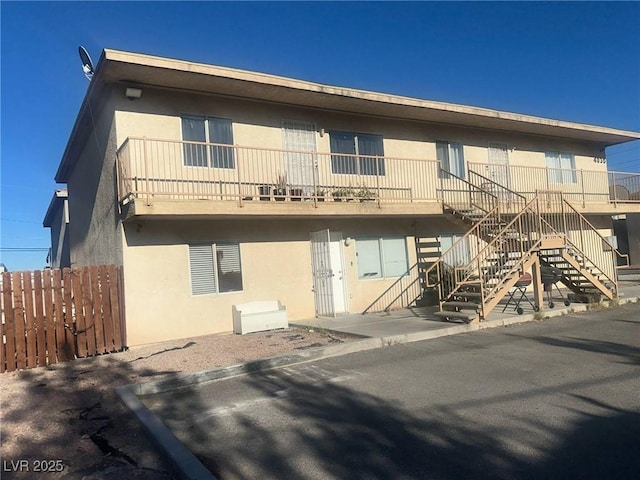 exterior space featuring stairway, fence, and stucco siding