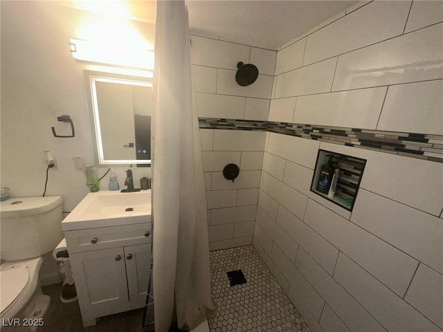 bathroom with vanity, a tile shower, and toilet