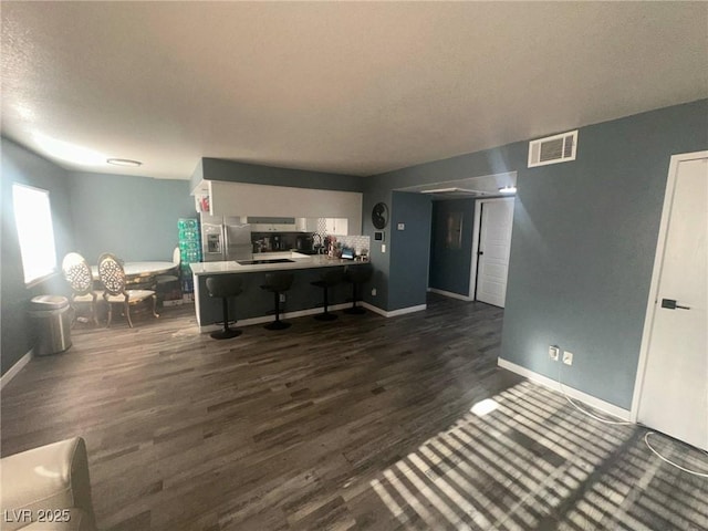 living area featuring baseboards, dark wood-style flooring, and visible vents
