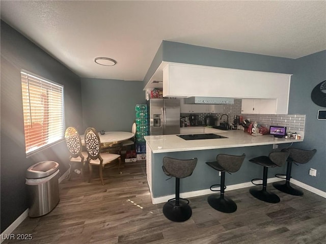 kitchen featuring stainless steel fridge, white cabinets, a peninsula, and dark wood-style flooring
