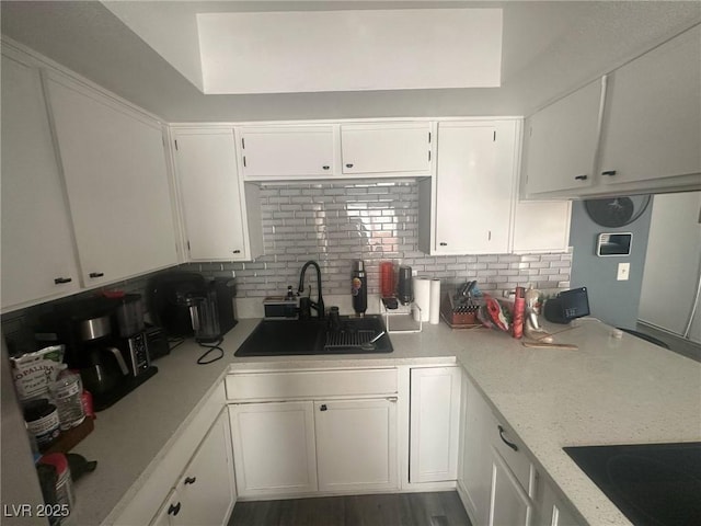 kitchen featuring a sink, decorative backsplash, black electric stovetop, and white cabinets