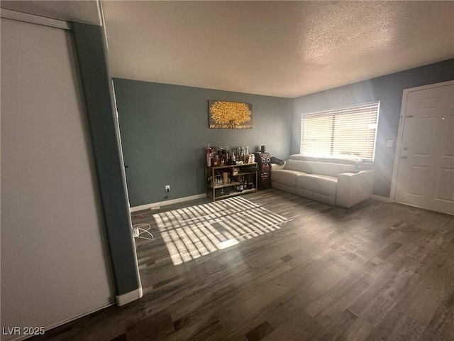 living room featuring baseboards, a textured ceiling, and wood finished floors