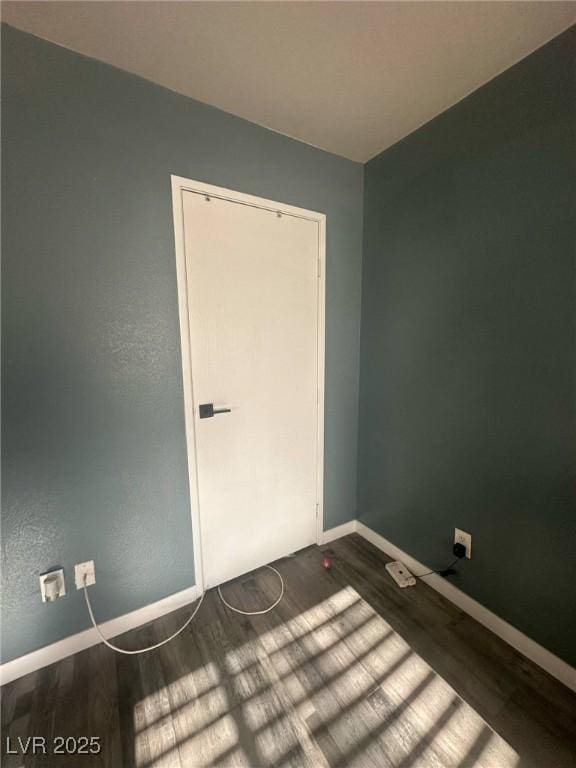spare room featuring baseboards and dark wood-style flooring