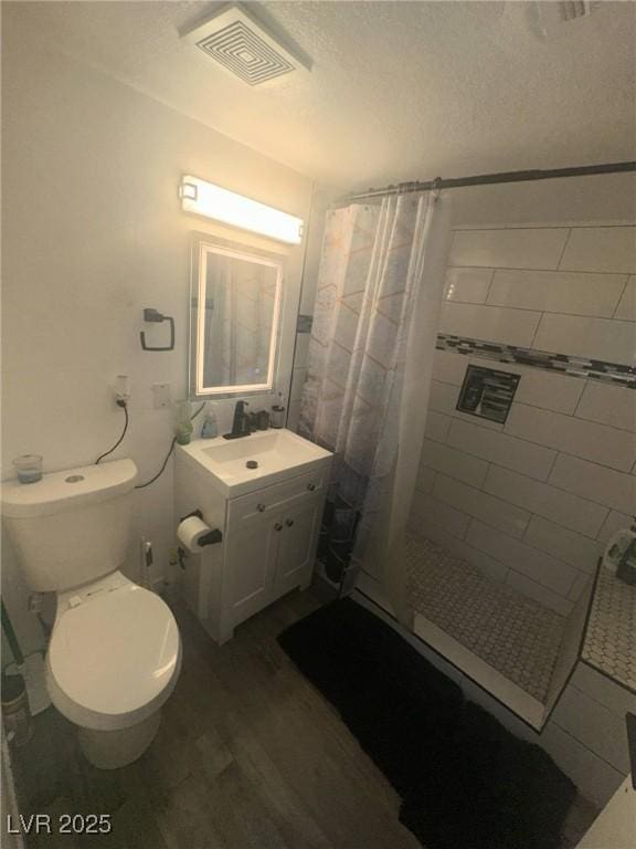 full bath featuring visible vents, a shower stall, wood finished floors, vanity, and toilet