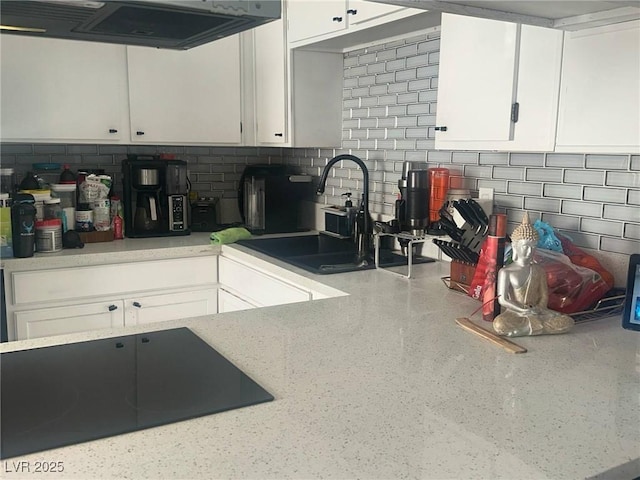 kitchen featuring white cabinets, a sink, light countertops, black electric cooktop, and extractor fan