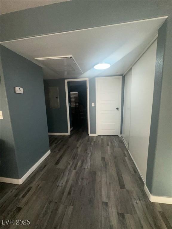 hallway with dark wood-style flooring, baseboards, attic access, and electric panel