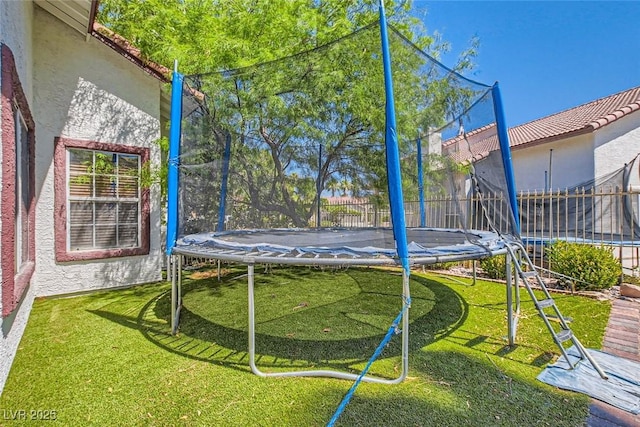 view of yard with a trampoline and fence private yard