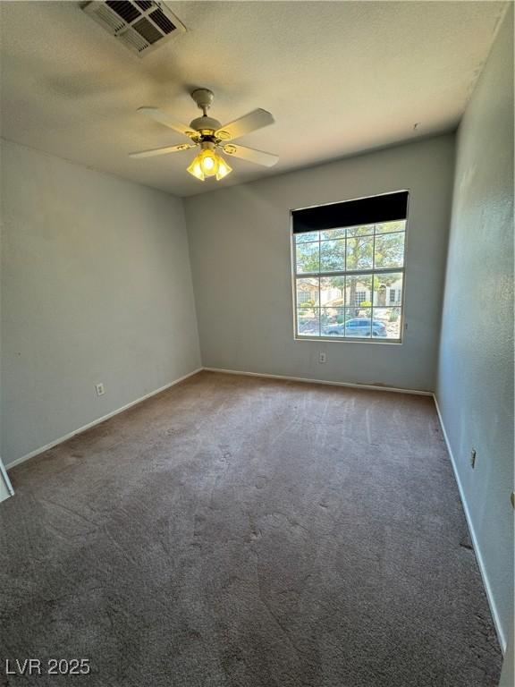 carpeted empty room featuring baseboards, a ceiling fan, and visible vents