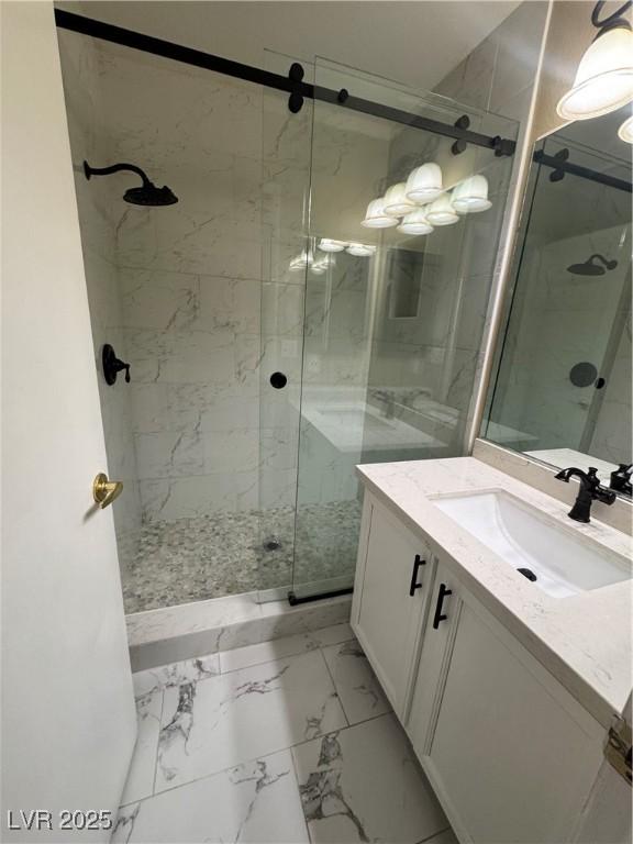 full bath with vanity, marble finish floor, and a stall shower