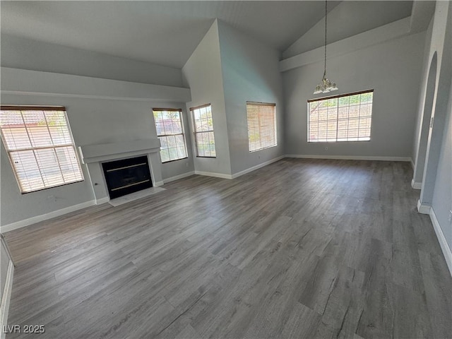unfurnished living room featuring a fireplace with flush hearth, an inviting chandelier, plenty of natural light, and wood finished floors
