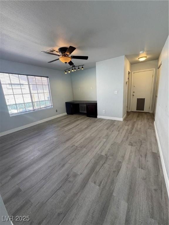 unfurnished living room featuring light wood-style floors, baseboards, and a ceiling fan