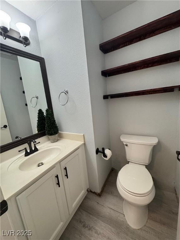 bathroom with vanity, toilet, and wood finished floors