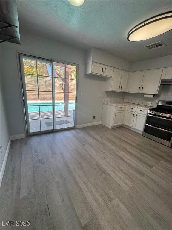 kitchen featuring baseboards, light wood-style floors, visible vents, and range with two ovens
