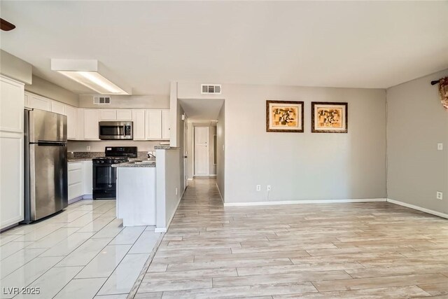 4955 Lindell Rd Unit 130, Las Vegas, NV 89118 - kitchen featuring appliances with stainless steel finishes, white cabinetry, baseboards, open floor plan, and light wood-style floors