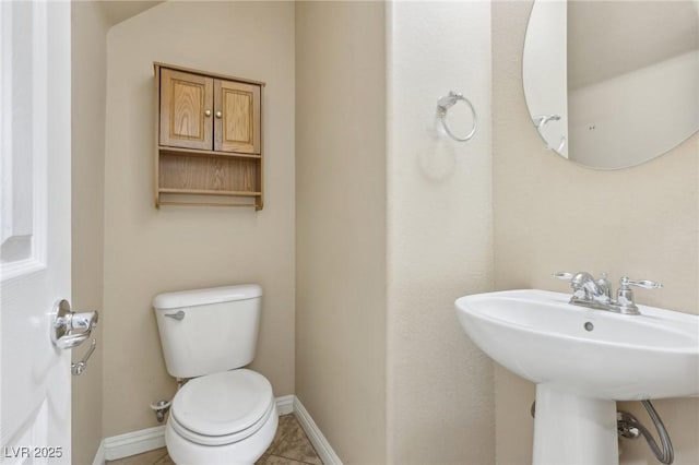 bathroom with a sink, baseboards, tile patterned flooring, and toilet