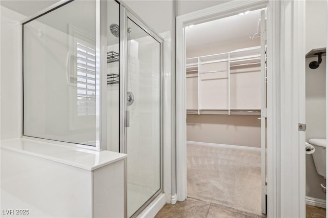 bathroom with baseboards, tile patterned flooring, a shower stall, and a spacious closet