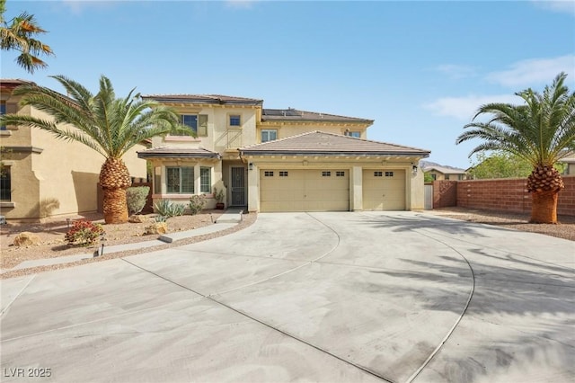 mediterranean / spanish home featuring solar panels, a garage, fence, concrete driveway, and stucco siding