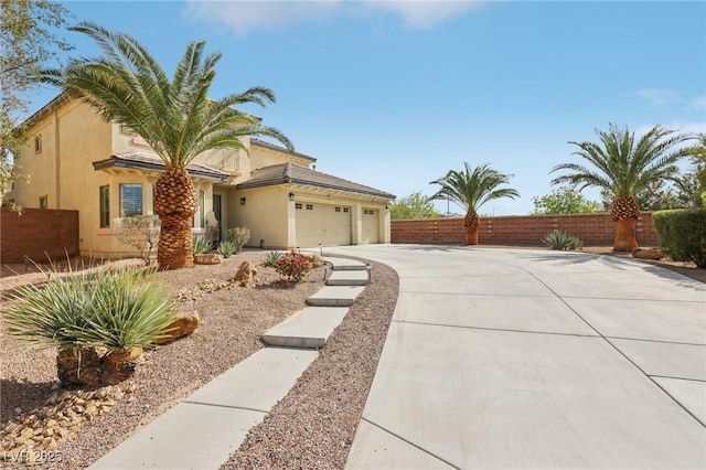 view of front of property with fence, stucco siding, concrete driveway, and a garage