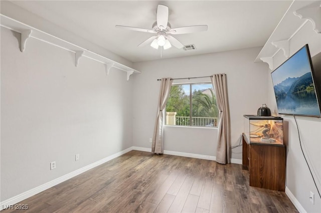empty room with baseboards, a ceiling fan, wood finished floors, and visible vents
