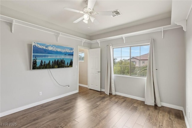 unfurnished bedroom featuring baseboards, ceiling fan, wood finished floors, and visible vents