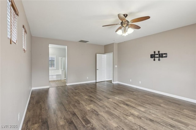 spare room with baseboards, a ceiling fan, wood finished floors, and visible vents