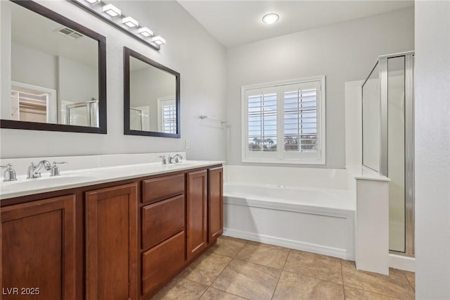 bathroom featuring visible vents, a sink, a bath, and a stall shower