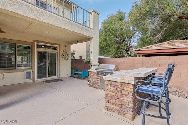 view of patio with fence, outdoor wet bar, an outdoor kitchen, grilling area, and a balcony