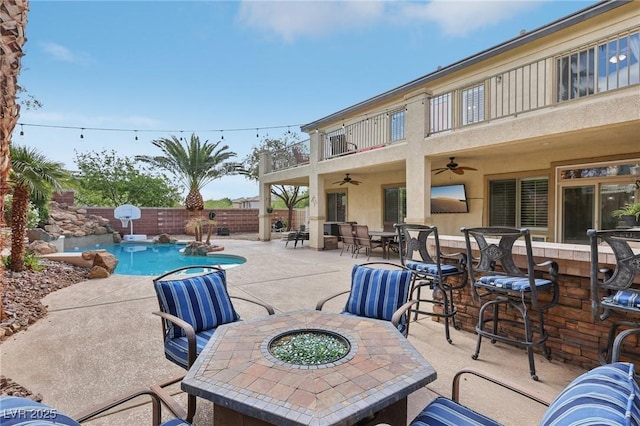 view of patio with ceiling fan, a fenced in pool, a fenced backyard, a fire pit, and outdoor dining space