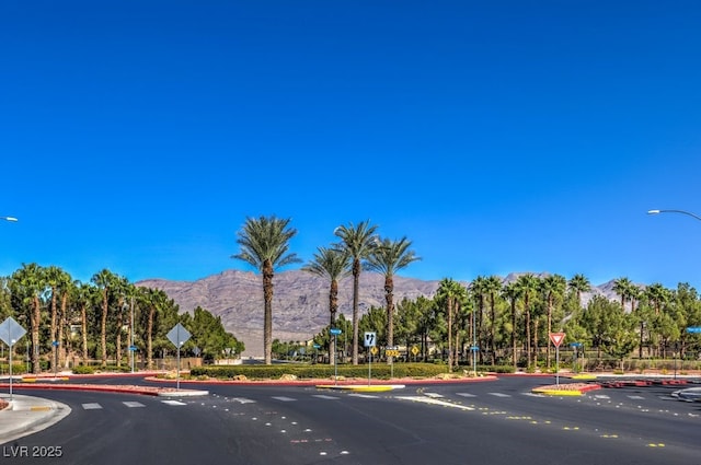 view of street with traffic signs, a mountain view, and curbs