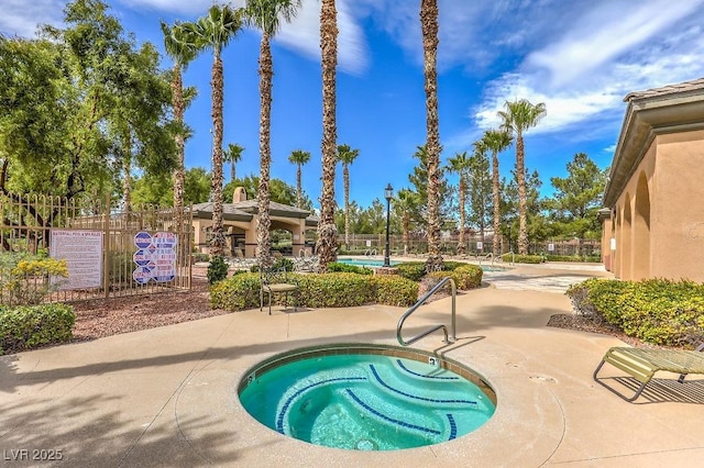 pool with fence, a hot tub, and a patio area